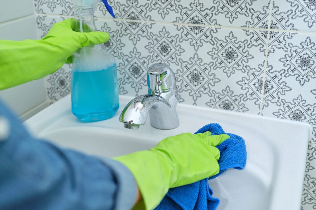 Woman in gloves with rag doing cleaning in bathroom